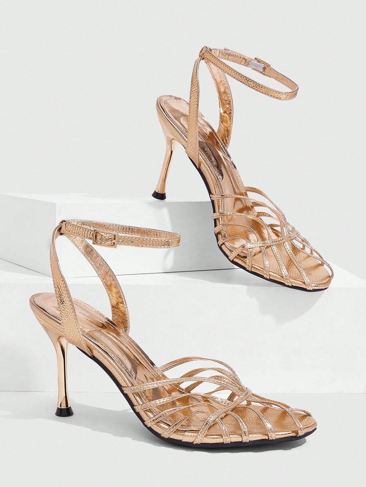 Women's glossy silver open-toed sandals with thin pyramid heel and strappy ribbon details.