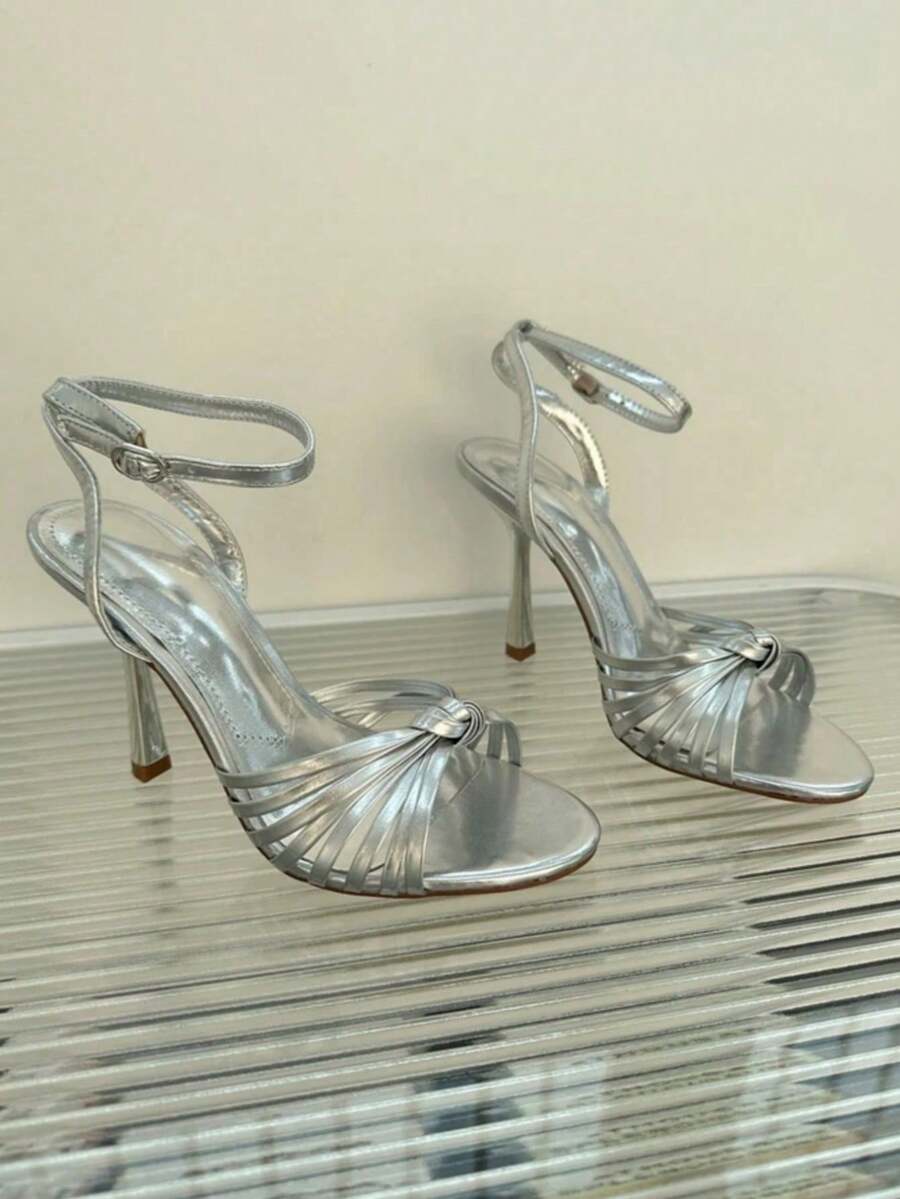 Women's open toe stiletto high heel sandals featuring metallic knot decor and an adjustable ankle buckle strap.