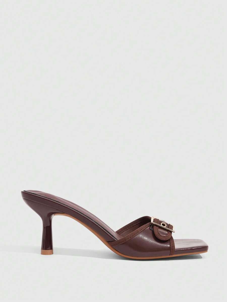 Beige women's slip-on kitten heel slide sandals featuring an accent buckle with grommet eyelets.