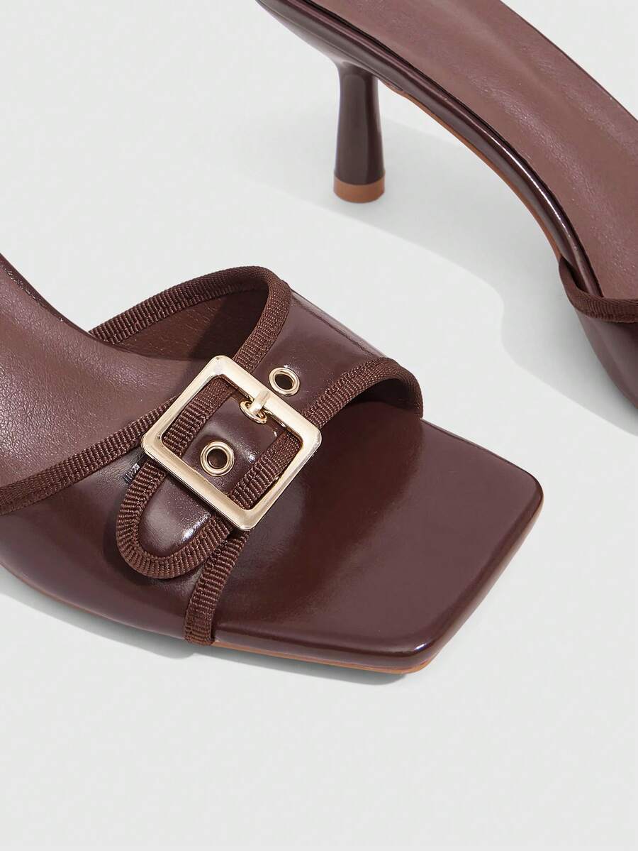 Beige women's slip-on kitten heel slide sandals featuring an accent buckle with grommet eyelets.