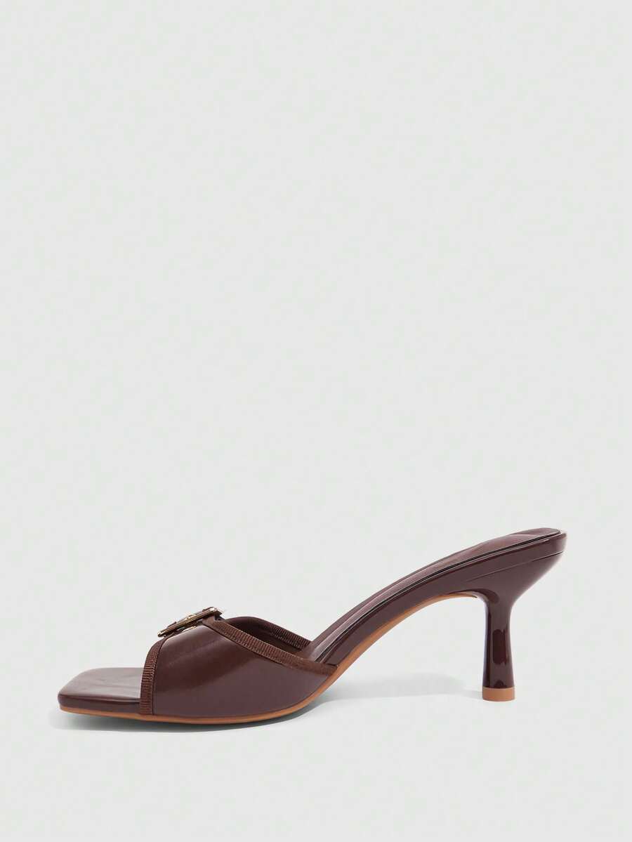 Beige women's slip-on kitten heel slide sandals featuring an accent buckle with grommet eyelets.