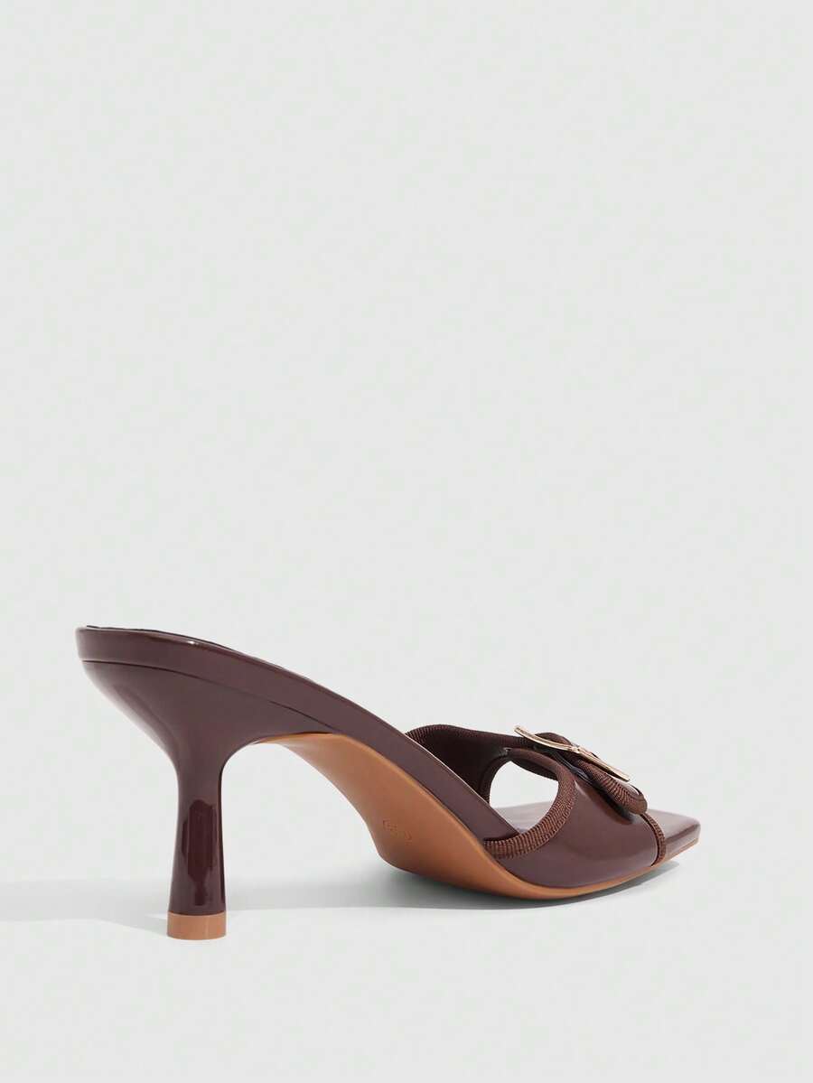 Beige women's slip-on kitten heel slide sandals featuring an accent buckle with grommet eyelets.