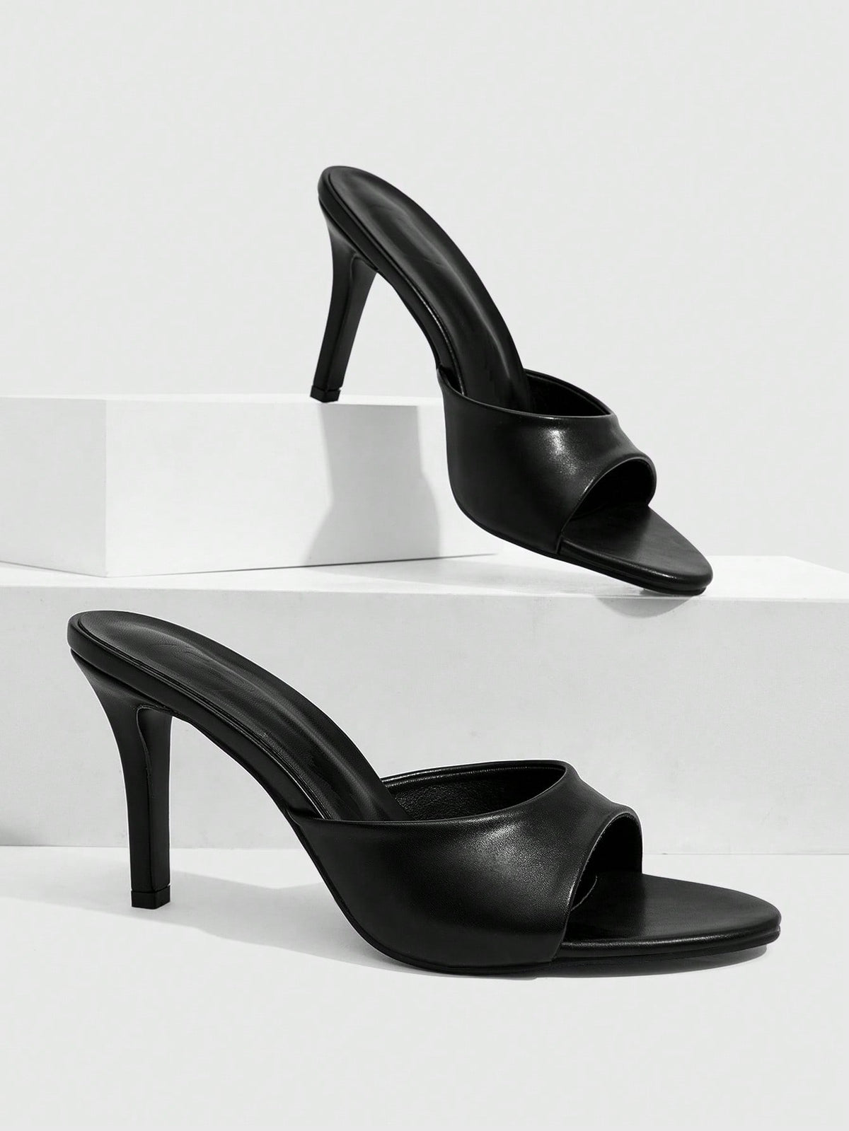 Pair of women's pointed toe stiletto mule sandals with shiny patent upper and slip-on design.