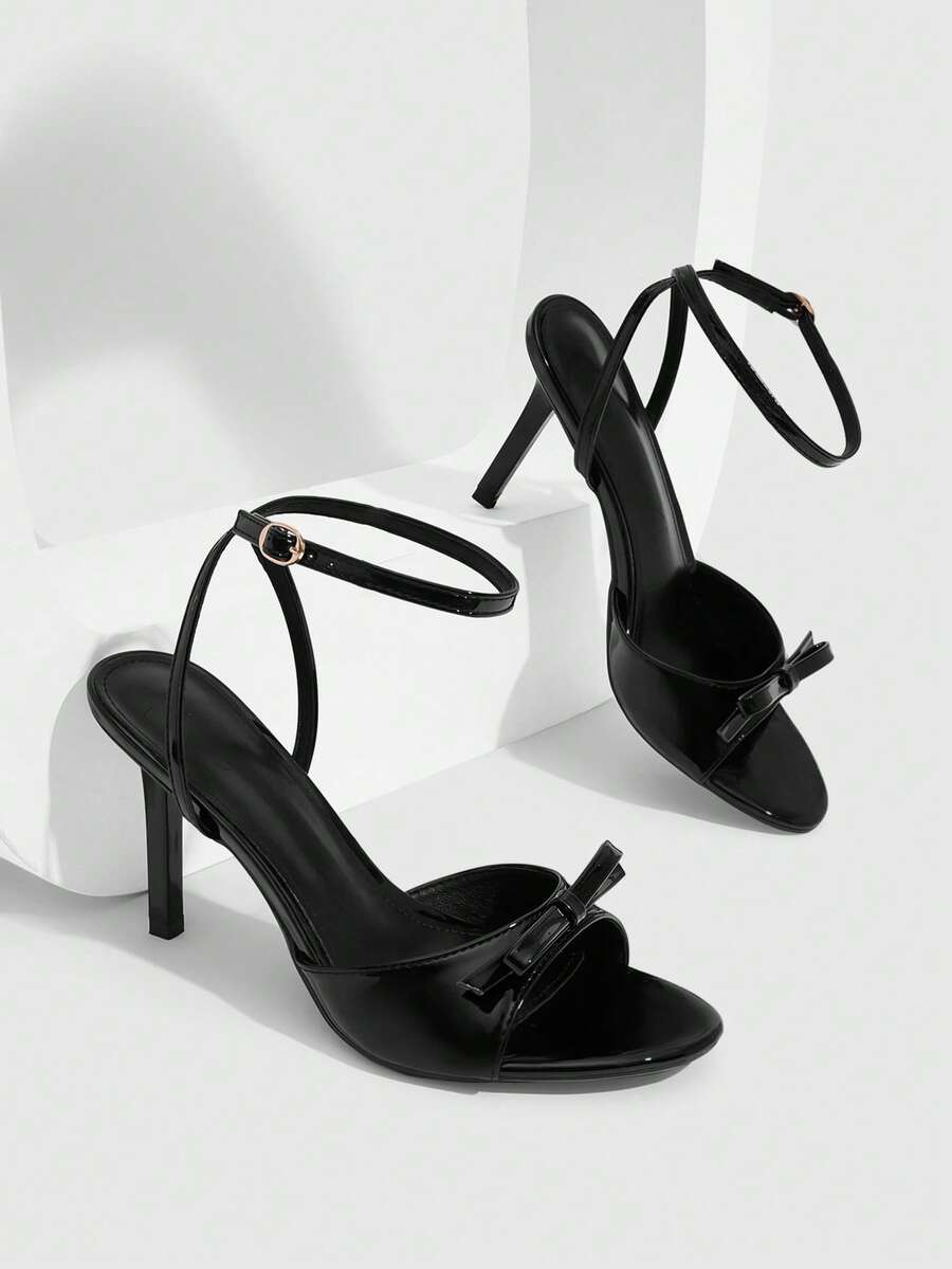Women's pointed peep toe high heel stilettos featuring cross ankle strap with buckle in black PU leather.