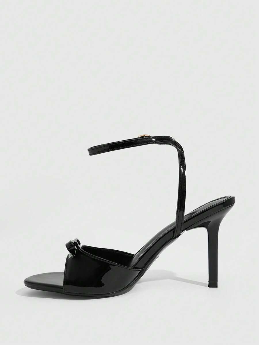 Women's pointed peep toe high heel stilettos featuring cross ankle strap with buckle in black PU leather.