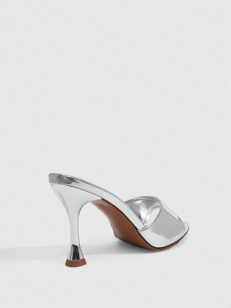 Pair of women's pointed toe stiletto mule sandals with shiny patent upper and slip-on design.