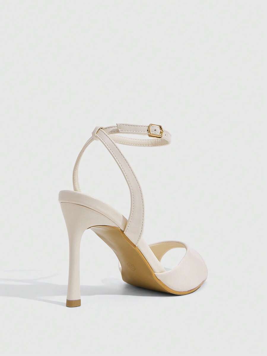 Women's pointed peep toe high heel stilettos featuring cross ankle strap with buckle in black PU leather.