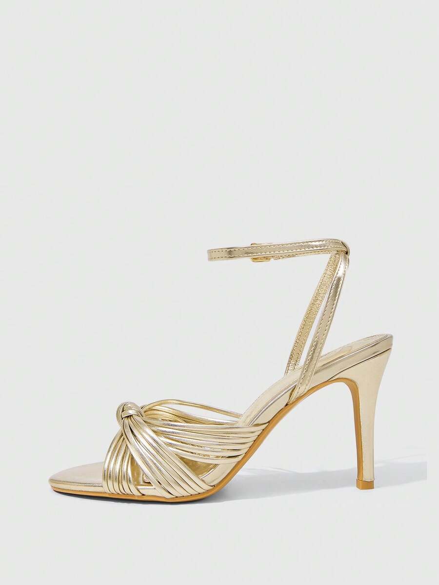 Women's champagne stiletto high heel sandals featuring knotted cross-over straps, open round toe, and adjustable ankle buckle strap.