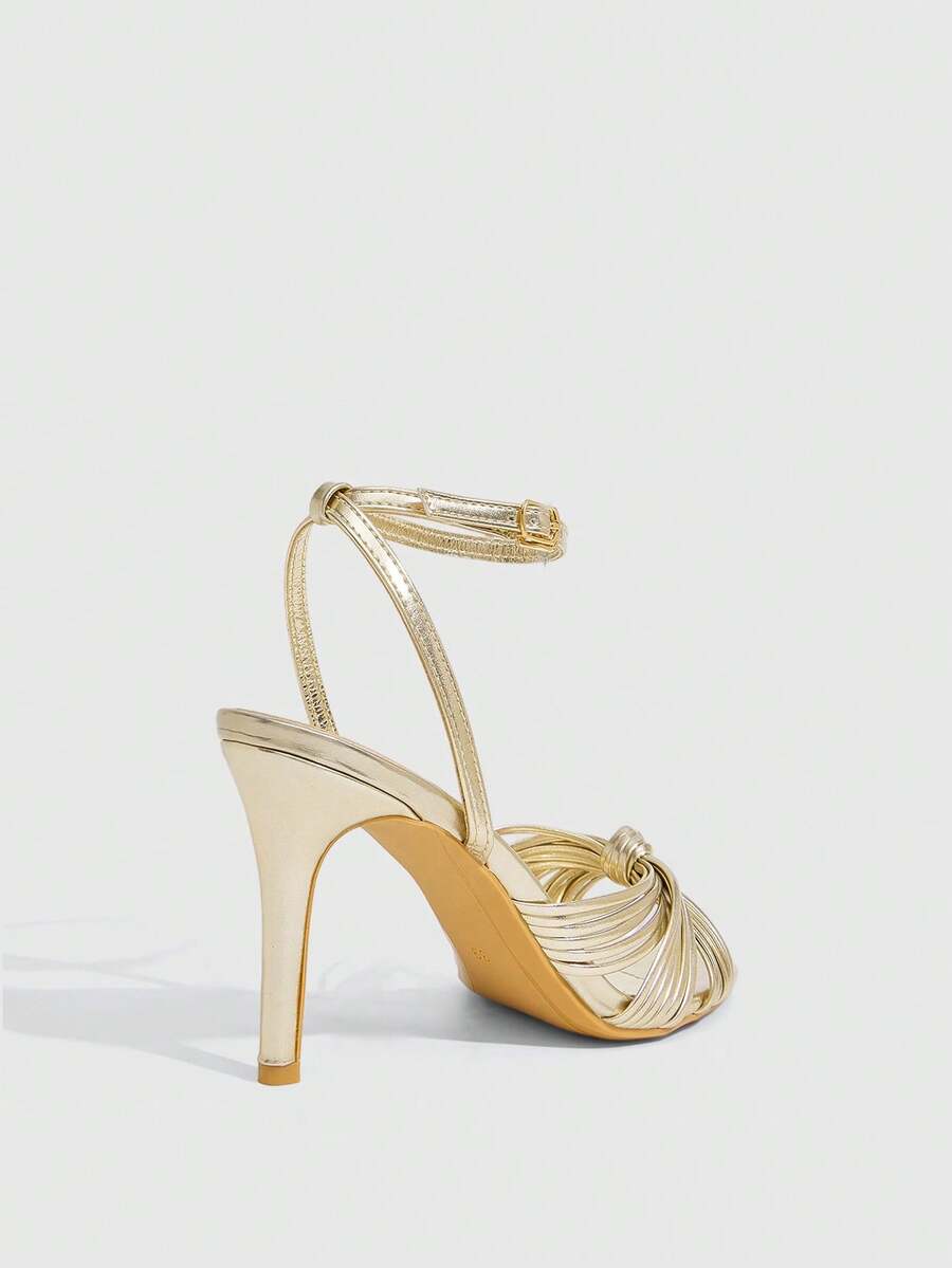 Women's champagne stiletto high heel sandals featuring knotted cross-over straps, open round toe, and adjustable ankle buckle strap.