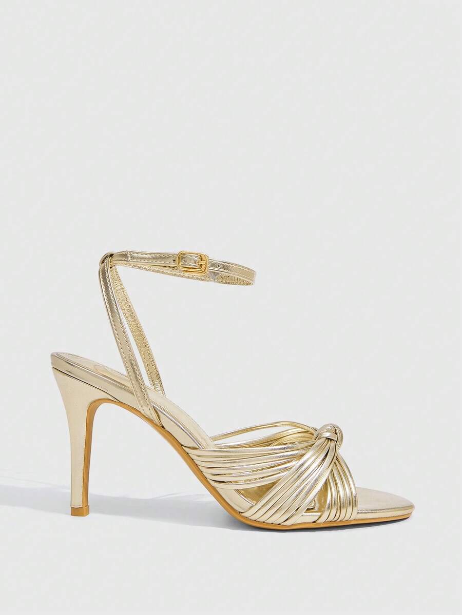 Women's champagne stiletto high heel sandals featuring knotted cross-over straps, open round toe, and adjustable ankle buckle strap.