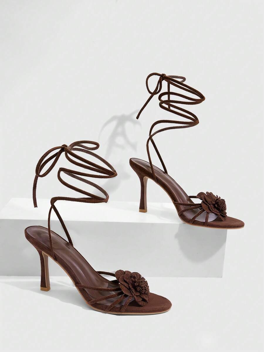 Women's round toe high heel sandals with brown flannel finish, floral trim detail, and strappy lace-up stiletto design.