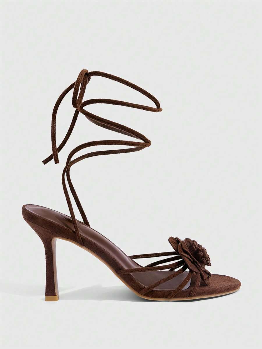 Women's round toe high heel sandals with brown flannel finish, floral trim detail, and strappy lace-up stiletto design.