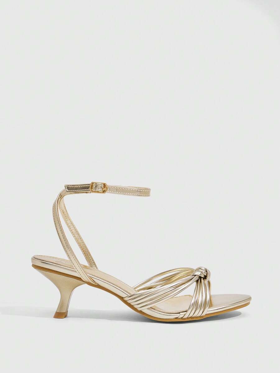 Women's champagne stiletto high heel sandals featuring knotted cross-over straps, open round toe, and adjustable ankle buckle strap.