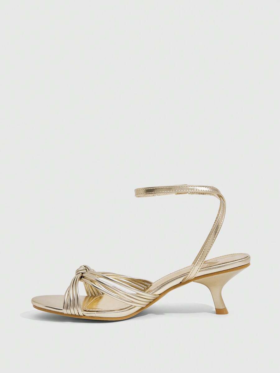 Women's champagne stiletto high heel sandals featuring knotted cross-over straps, open round toe, and adjustable ankle buckle strap.