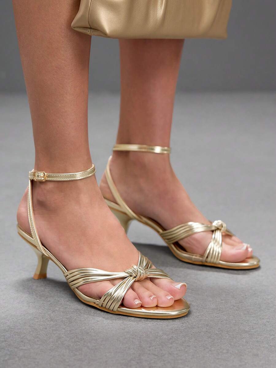 Women's champagne stiletto high heel sandals featuring knotted cross-over straps, open round toe, and adjustable ankle buckle strap.