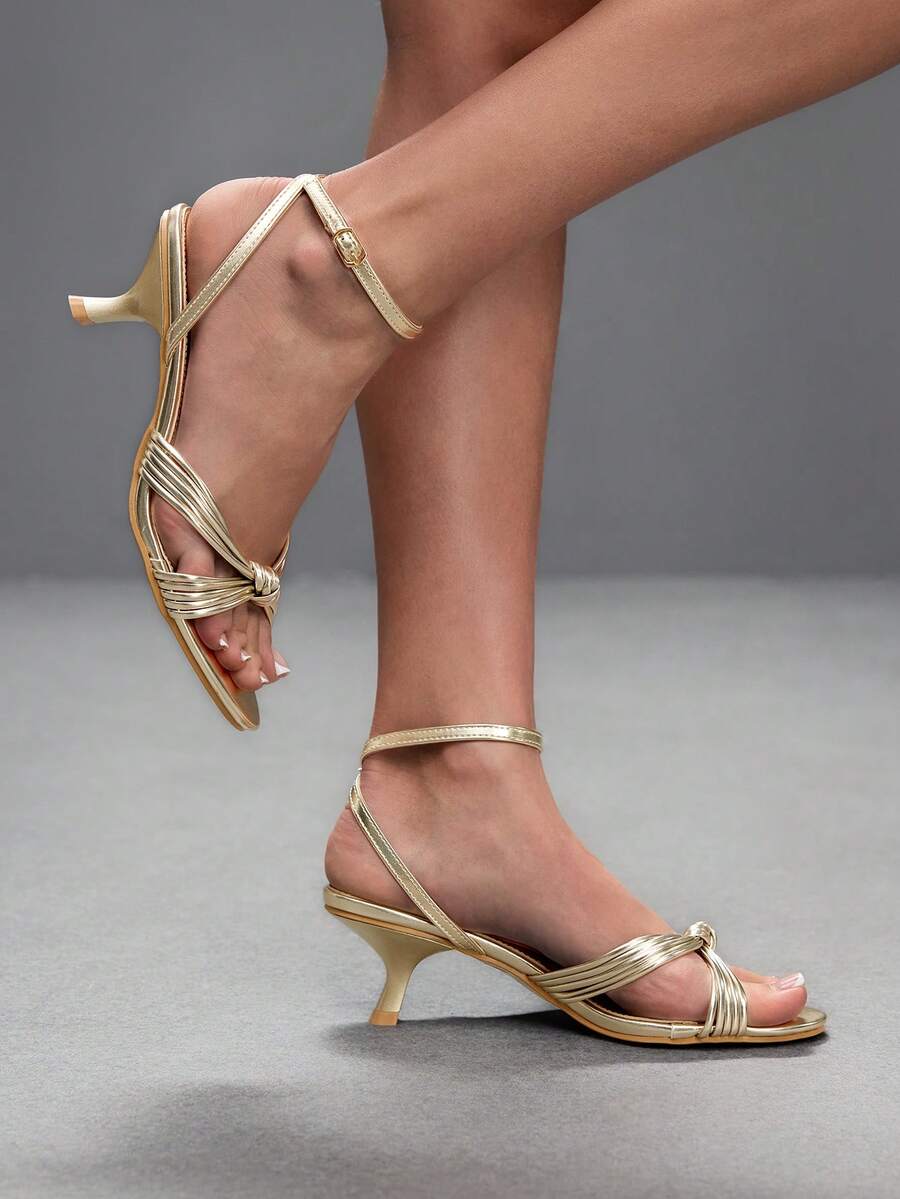 Women's champagne stiletto high heel sandals featuring knotted cross-over straps, open round toe, and adjustable ankle buckle strap.