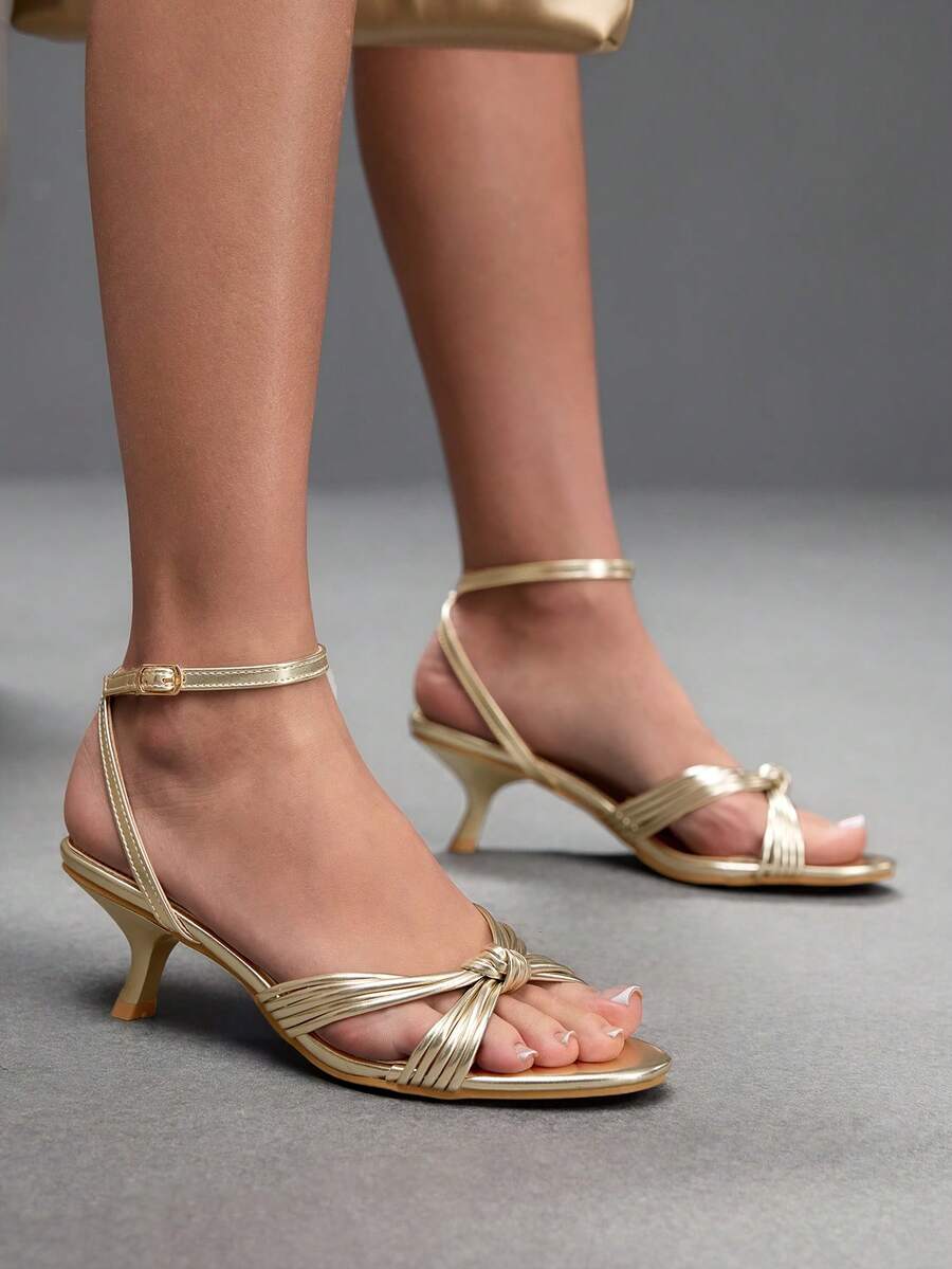 Women's champagne stiletto high heel sandals featuring knotted cross-over straps, open round toe, and adjustable ankle buckle strap.