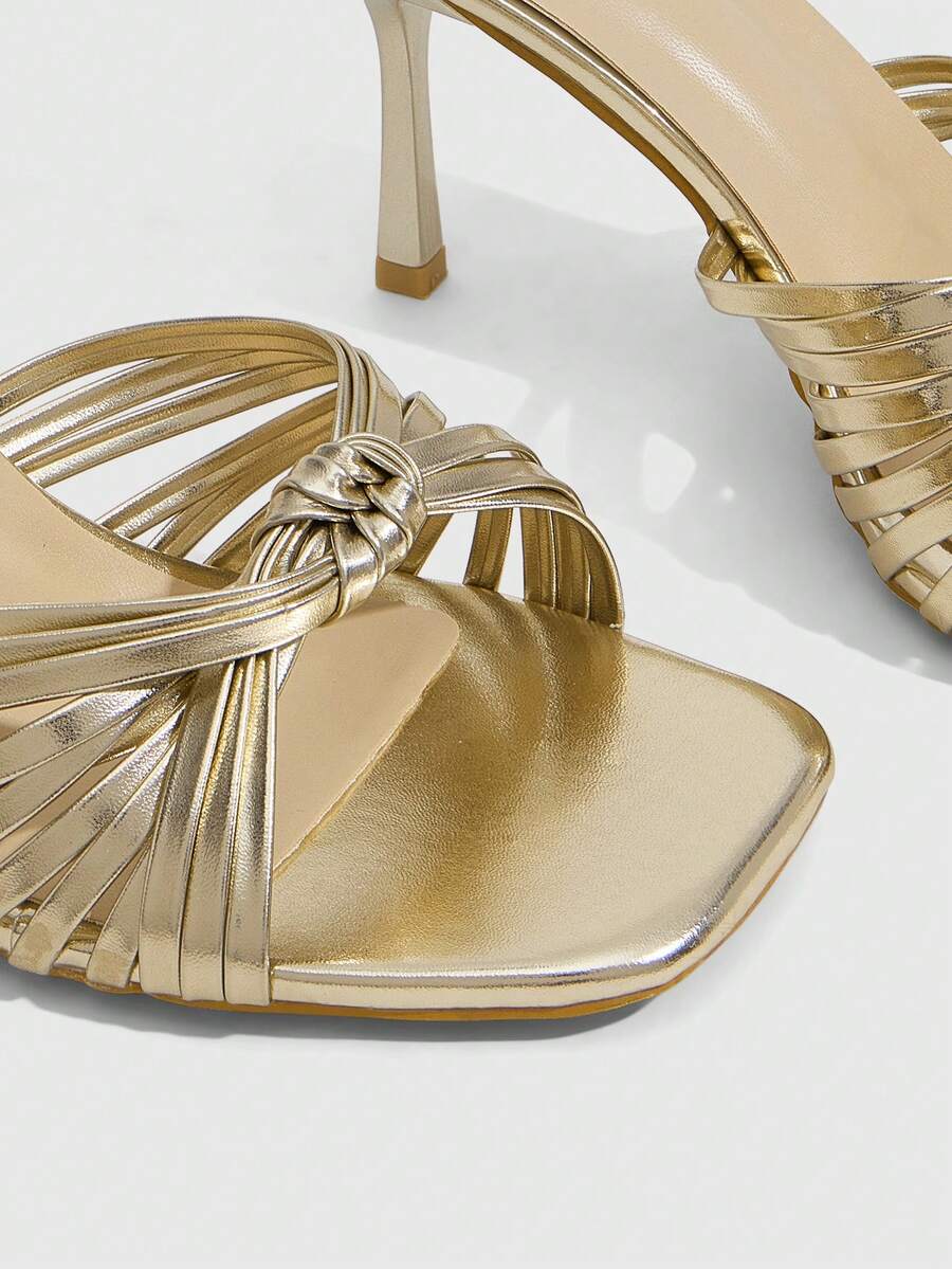 Women's champagne stiletto high heel sandals featuring knotted cross-over straps, open round toe, and adjustable ankle buckle strap.
