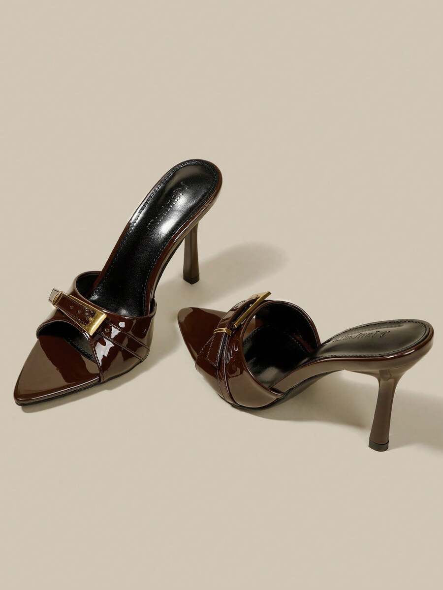Black patent leather pointed toe mule sandals featuring stiletto high heels and decorative buckle detail for evening parties