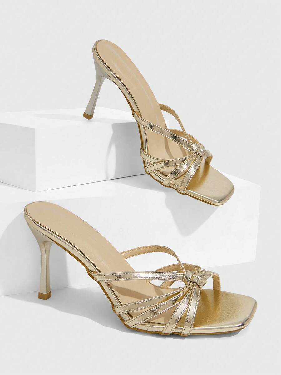 Women's champagne stiletto high heel sandals featuring knotted cross-over straps, open round toe, and adjustable ankle buckle strap.