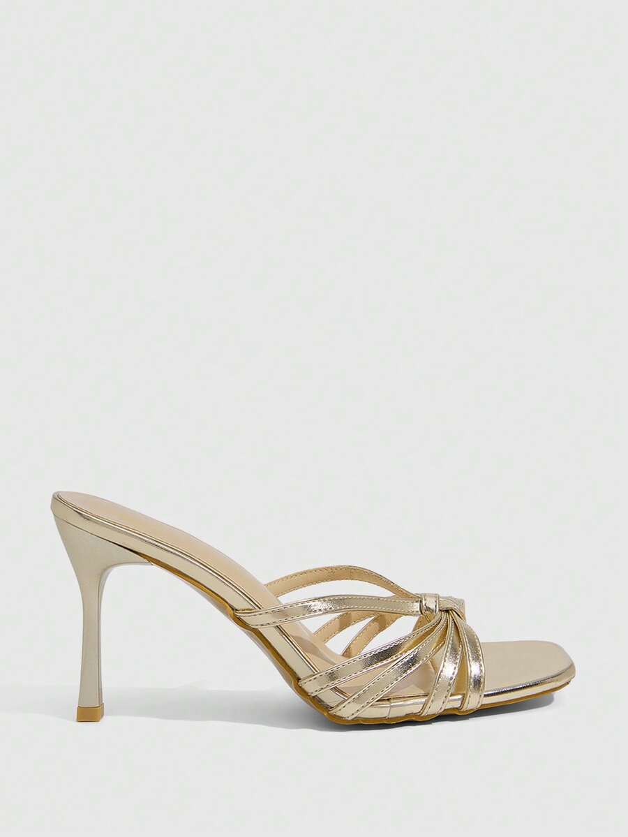 Women's champagne stiletto high heel sandals featuring knotted cross-over straps, open round toe, and adjustable ankle buckle strap.