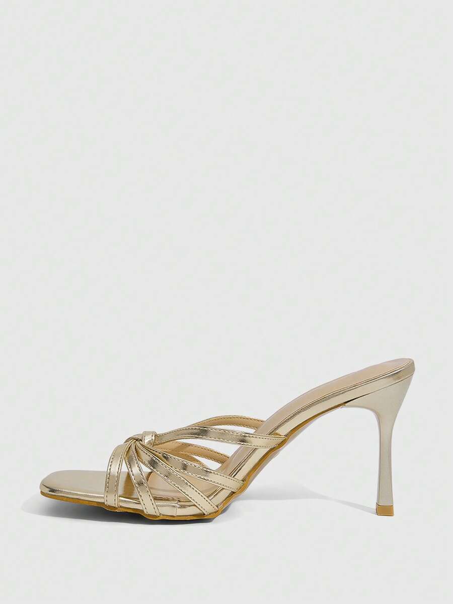 Women's champagne stiletto high heel sandals featuring knotted cross-over straps, open round toe, and adjustable ankle buckle strap.