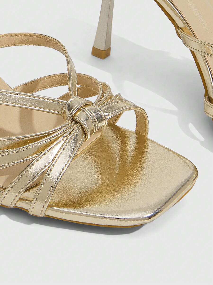 Women's champagne stiletto high heel sandals featuring knotted cross-over straps, open round toe, and adjustable ankle buckle strap.