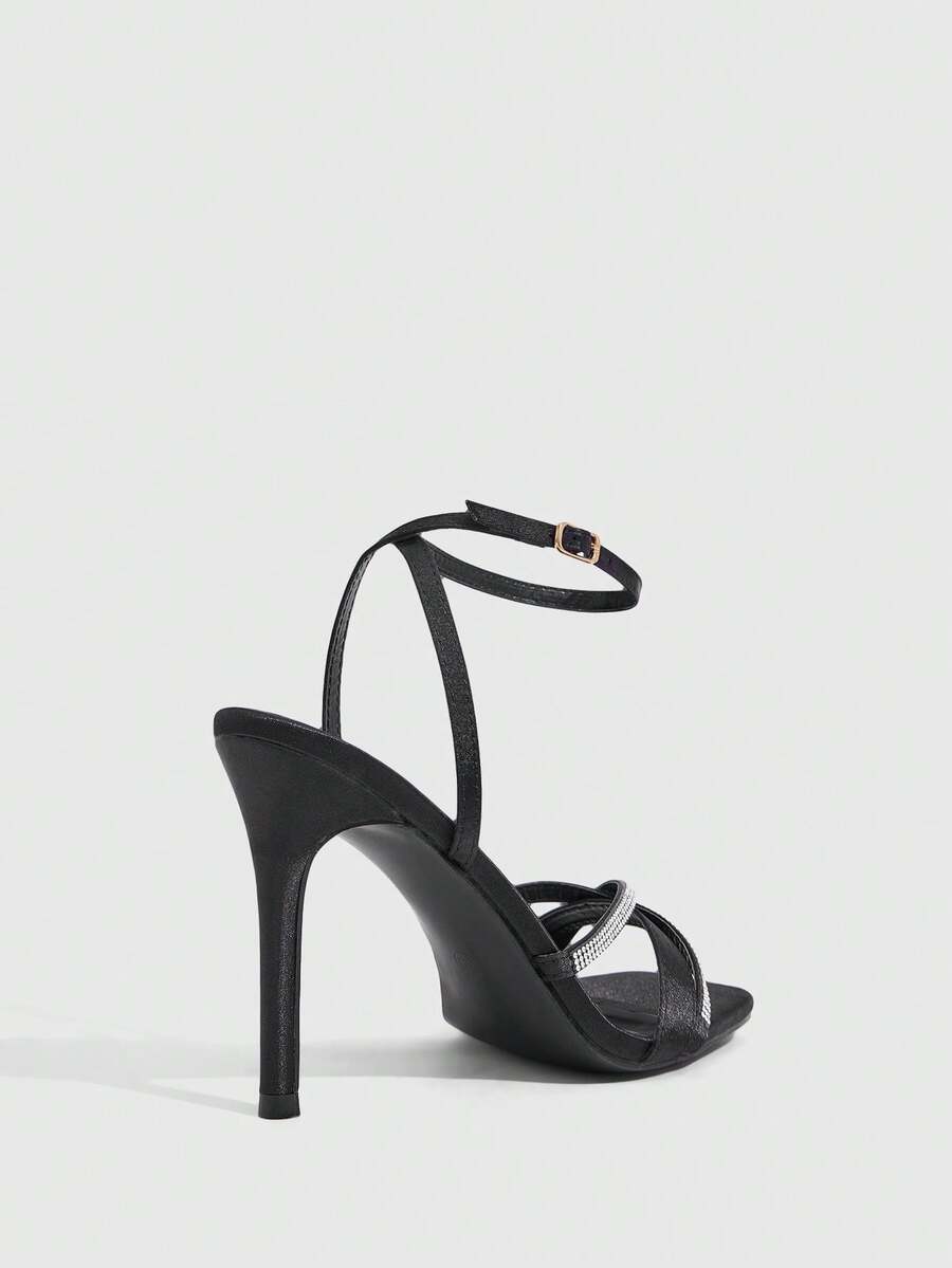 Women's pointed peep toe high heel stilettos featuring cross ankle strap with buckle in black PU leather.