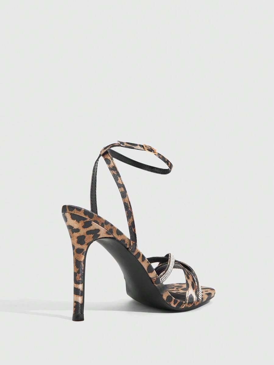 Women's pointed peep toe high heel stilettos featuring cross ankle strap with buckle in black PU leather.