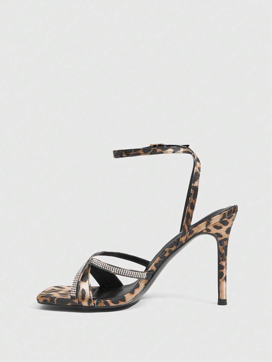 Women's pointed peep toe high heel stilettos featuring cross ankle strap with buckle in black PU leather.