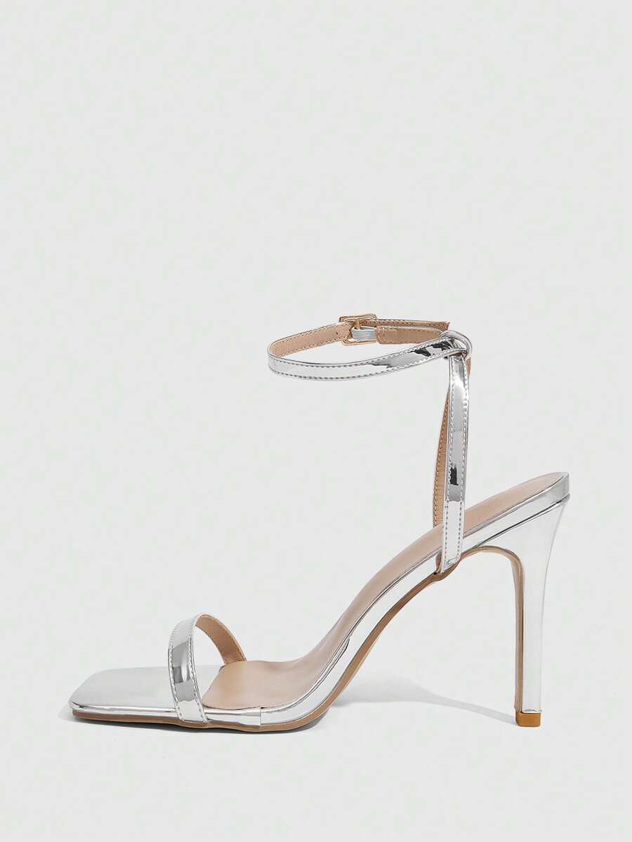 Women's minimalist black heeled sandals featuring an open toe, stiletto high heel, and adjustable ankle strap buckle closure.