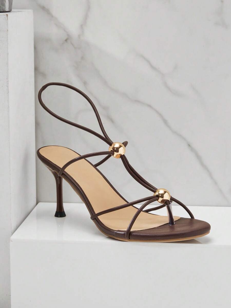 Women's strappy stiletto heel sandals crafted in vegan PU leather featuring open toe design and metallic bead accents.