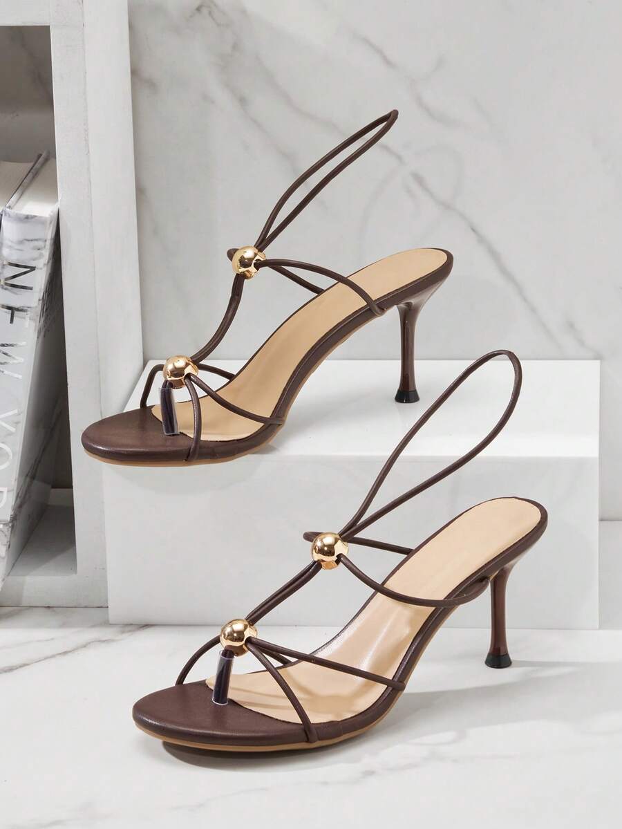 Women's strappy stiletto heel sandals crafted in vegan PU leather featuring open toe design and metallic bead accents.