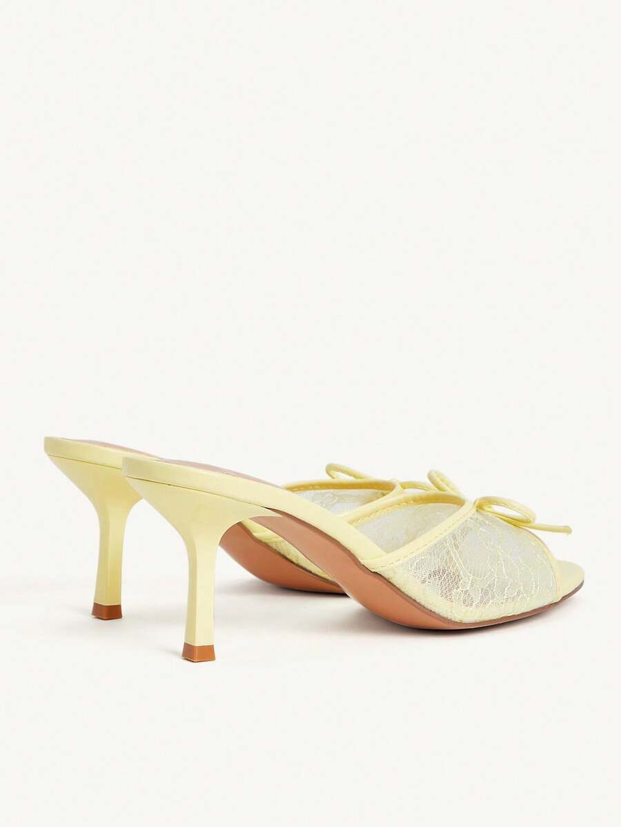 Open toe high heel slide sandals featuring lace details and a bow accent on the upper strap.