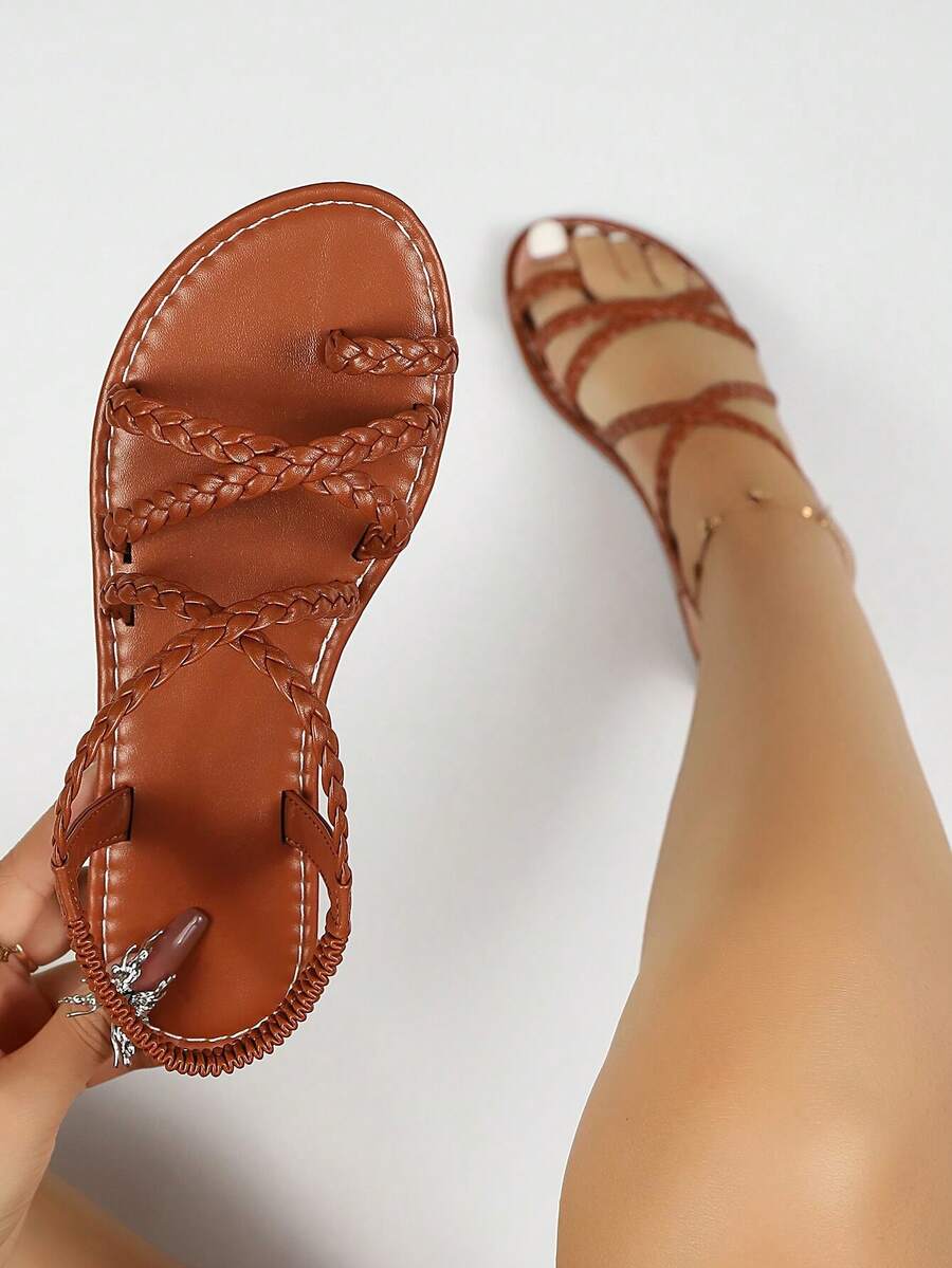 Flat sandals featuring thin criss-cross straps, elastic back strap, round toe post design, and smooth flat rubber sole.