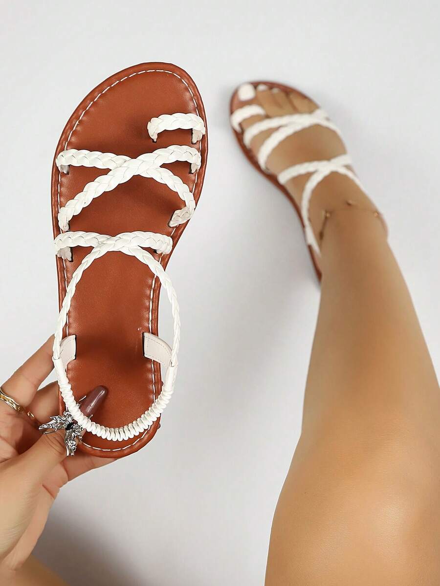 Flat sandals featuring thin criss-cross straps, elastic back strap, round toe post design, and smooth flat rubber sole.