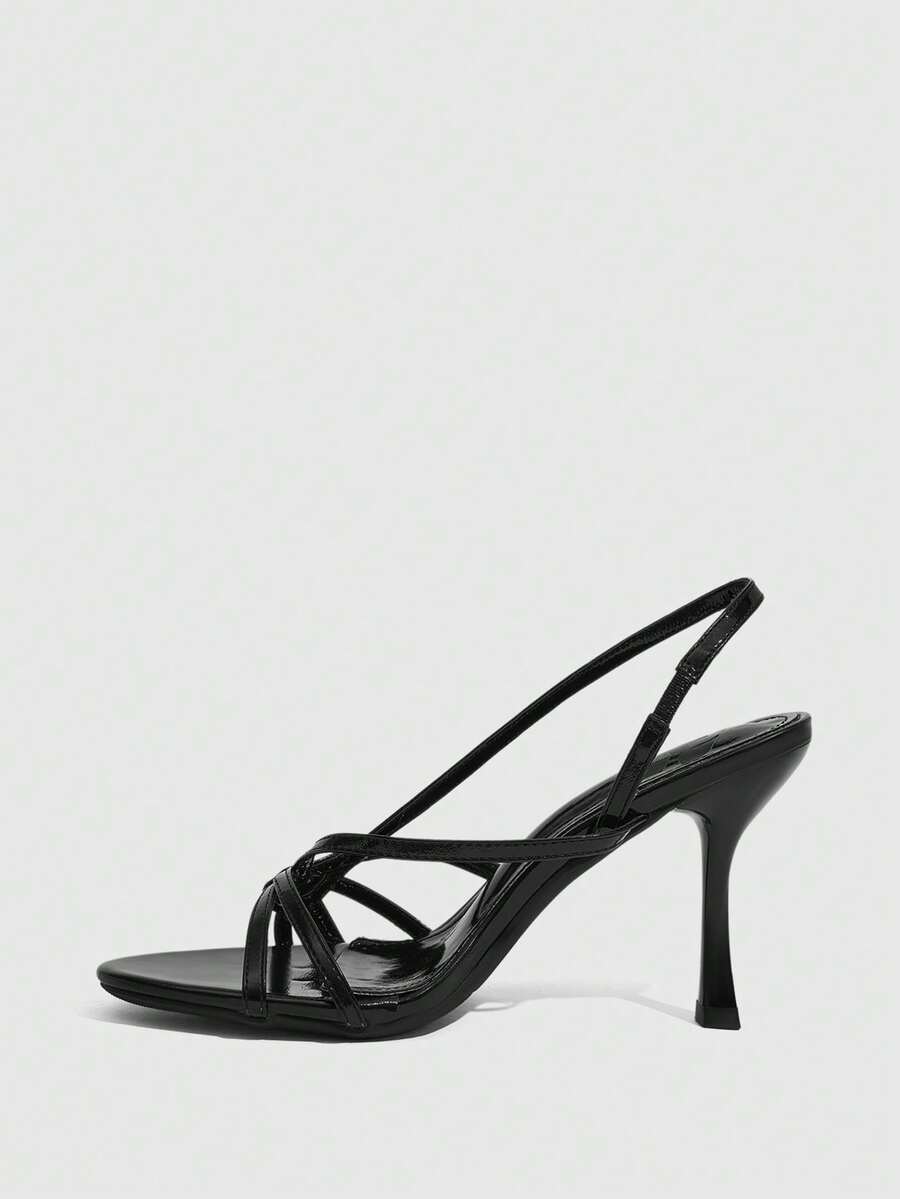 Women's open-toed stiletto high-heeled sandals in glossy patent black featuring twist strap detailing and slingback design.