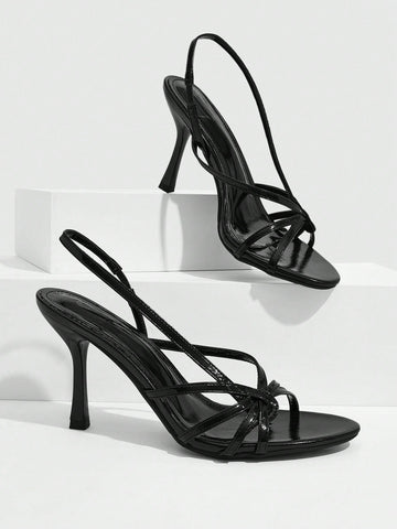 Women's open-toed stiletto high-heeled sandals in glossy patent black featuring twist strap detailing and slingback design.