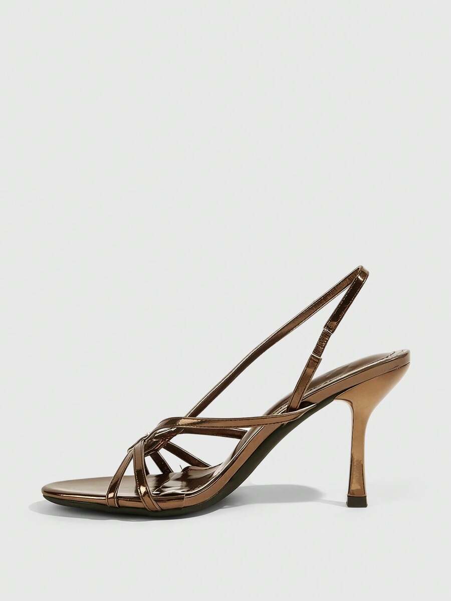 Women's open-toed stiletto high-heeled sandals in glossy patent black featuring twist strap detailing and slingback design.