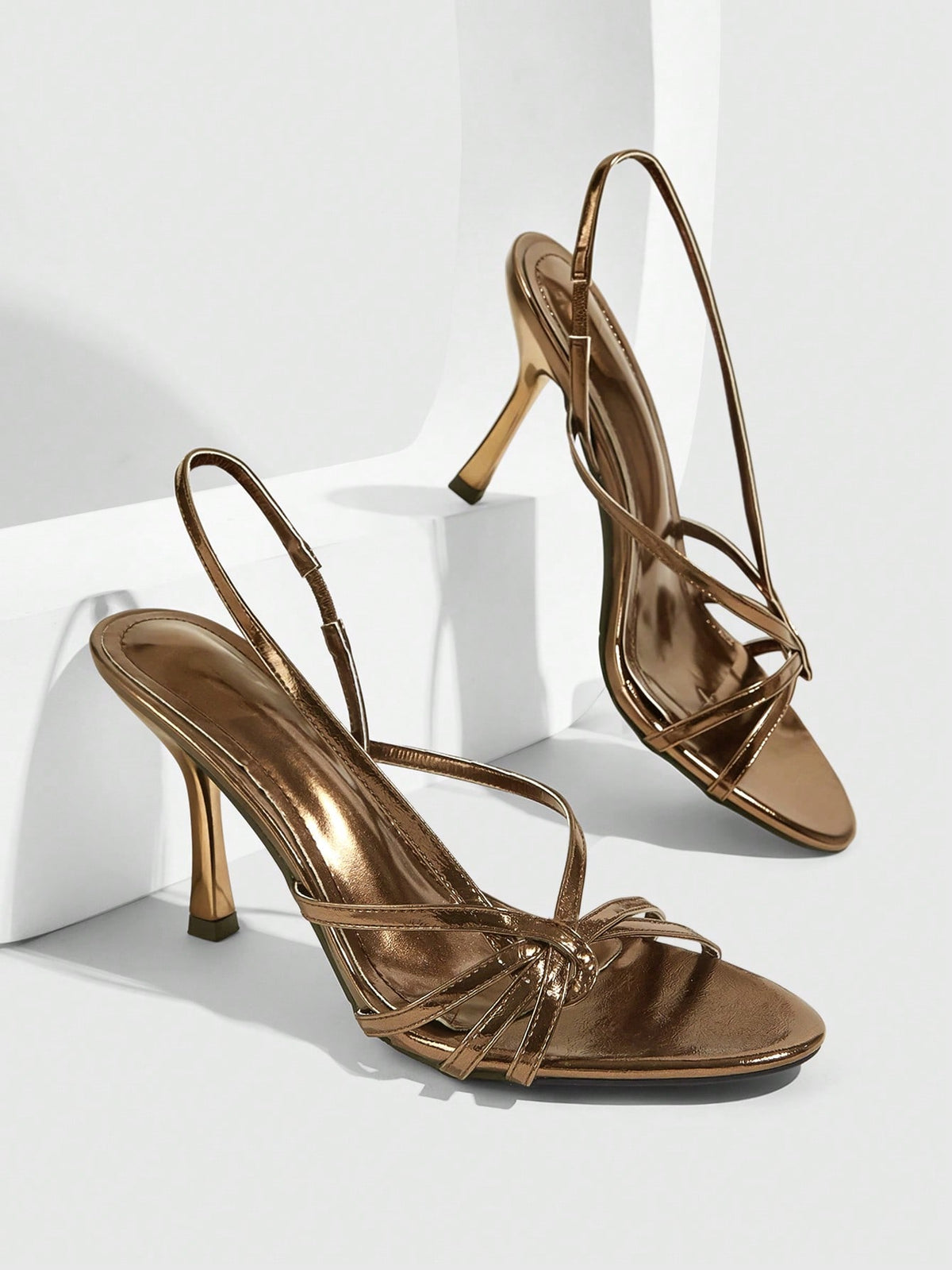 Women's open-toed stiletto high-heeled sandals in glossy patent black featuring twist strap detailing and slingback design.