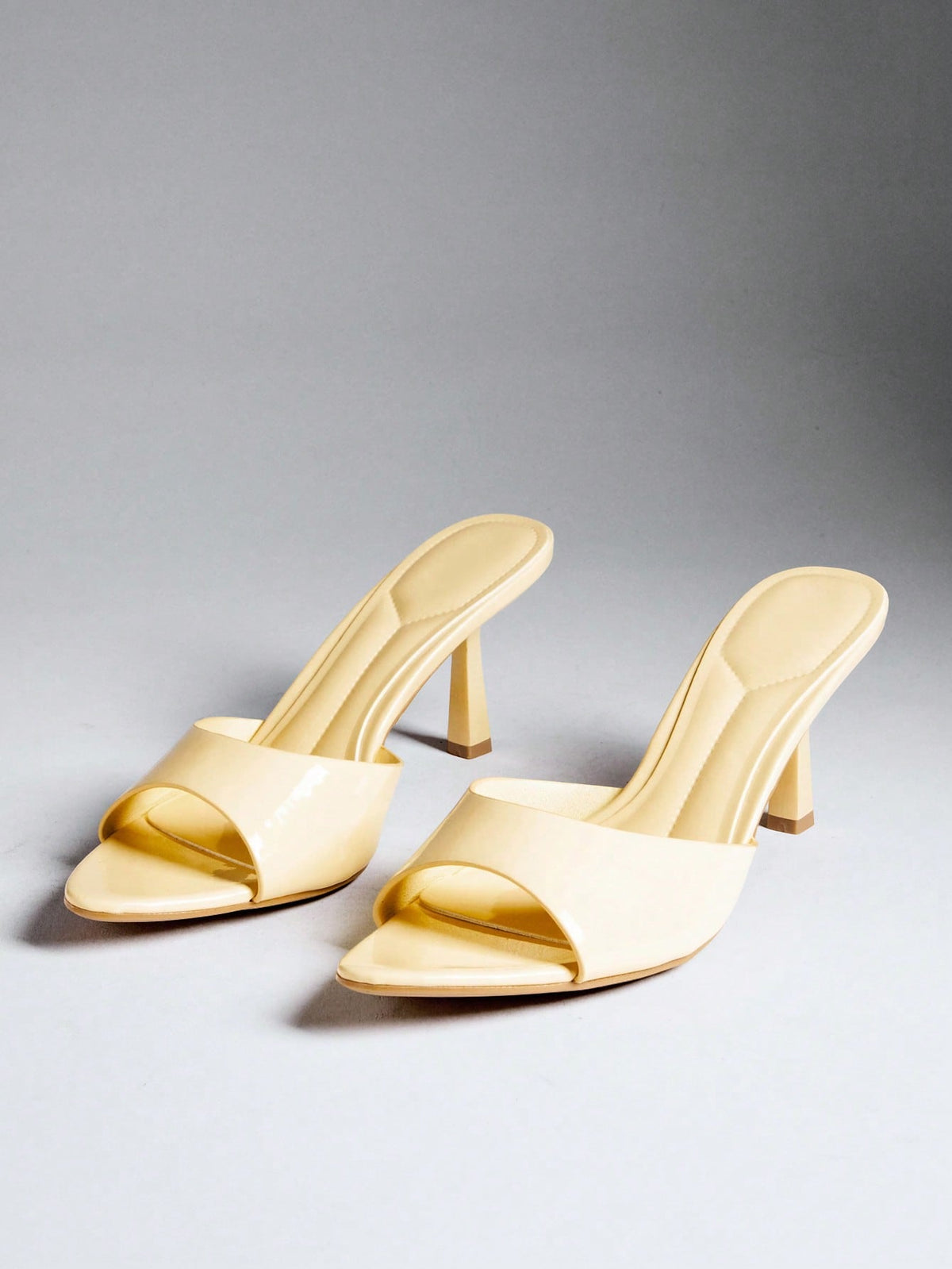 Black pointy toe kitten heel shoes for women featuring a sleek cut out mule design and glossy patent leather finish.