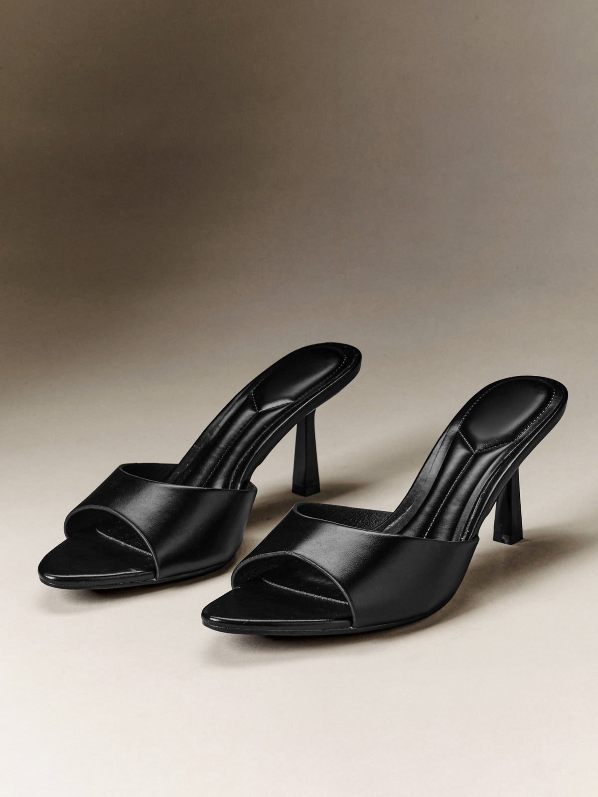 Pair of women's minimalist black pointy toe stiletto heel sandals with slingback straps.